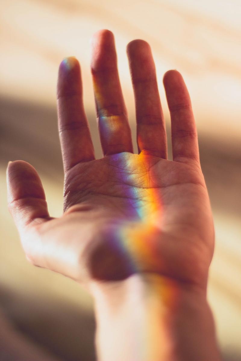 Mano con riflesso della luce color arcobaleno